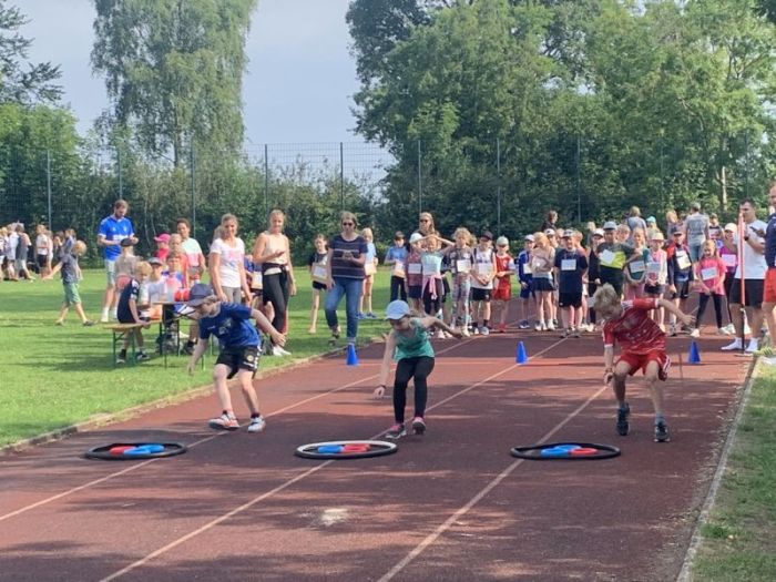 Kinder laufen auf der Laufbahn des Sportplatzes.